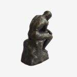 Miniature bronze sculpture of Rodin’s Thinking Man, resting on a marble base, symbolizing philosophical contemplation.