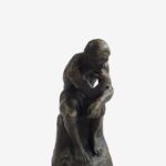 Miniature bronze sculpture of Rodin’s Thinking Man, resting on a marble base, symbolizing philosophical contemplation.