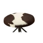 FORGE Barstool with a black metal frame and round brown and white cowhide upholstered seat, combining rustic and industrial style.