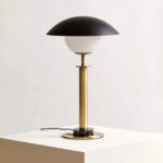 MONARCH Gold Table Lamp with a polished gold body, black marble base, glass globe, and a flying saucer-style black shade.