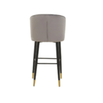 RUNE Barstool with grey velvet upholstery, cushioned seat, curved backrest, and sleek black legs with gold-tipped accents.