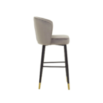 RUNE Barstool with grey velvet upholstery, cushioned seat, curved backrest, and sleek black legs with gold-tipped accents.