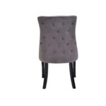 Grey velvet dining chair with button-tufted backrest, stud detailing, and solid black wood legs.