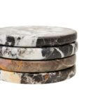 Set of four round black marble coasters with white veining, perfect for protecting surfaces in modern interiors.