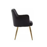 Black velvet dining chair with padded seat, quilted back, cocooning armrests, and gold splayed metal legs.