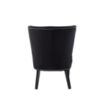 Black velvet dining chair with a wingback design, deep-cushioned seat, black wood legs, and stud detail trim.