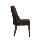 Black velvet dining chair with button-tufted backrest, warm metallic stud detailing, and dark wooden legs.