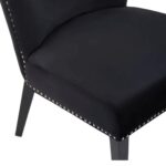 Black velvet dining chair with a wingback design, deep-cushioned seat, black wood legs, and stud detail trim.