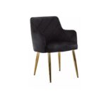 Black velvet dining chair with padded seat, quilted back, cocooning armrests, and gold splayed metal legs.