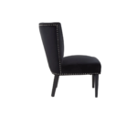 Black velvet dining chair with a wingback design, deep-cushioned seat, black wood legs, and stud detail trim.