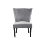 Grey velvet dining chair with a wingback design, deep-cushioned seat, black wood legs, and stud detail trim.