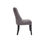 Grey velvet dining chair with button-tufted backrest, stud detailing, and solid black wood legs.