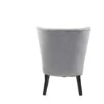 Grey velvet dining chair with a wingback design, deep-cushioned seat, black wood legs, and stud detail trim.