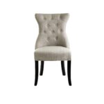 Grey linen dining chair with button tufting, black wooden legs, and a decorative metal knocker on the back.