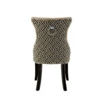 Grey linen dining chair with button tufting, black wooden legs, and a decorative metal knocker on the back.