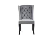 Grey velvet dining chair with a button-tufted wingback, padded seat, stud trim detailing, and curved black wood legs.