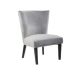 Grey velvet dining chair with a wingback design, deep-cushioned seat, black wood legs, and stud detail trim.