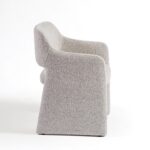 Modern dining chair upholstered in greyish bouclé fabric with a curved, architectural design and integrated arms.