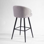 Sand-coloured upholstered barstool with curved backrest and black metal legs for stylish and comfortable high seating.