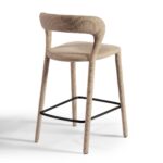 Modern taupe upholstered barstool with curved backrest and black metal footrest, ideal for kitchen islands and bar counters.
