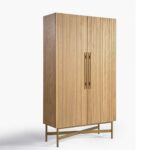 Tall oak cabinet with slatted wooden doors, gold metal base and handles, modern storage solution in natural finish.