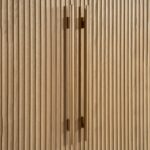 Tall oak cabinet with slatted wooden doors, gold metal base and handles, modern storage solution in natural finish.