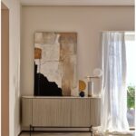 Greyish-white oak sideboard with white stone top, slatted wood door detailing, and black metal legs—sophisticated storage furniture for modern interiors.