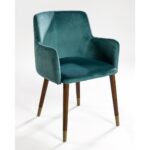Elegant peacock blue velvet armchair with curved backrest, padded seat, and wooden legs with metallic inserts, designed for modern interiors.