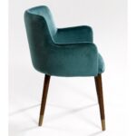 Elegant peacock blue velvet armchair with curved backrest, padded seat, and wooden legs with metallic inserts, designed for modern interiors.