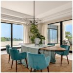Elegant peacock blue velvet armchair with curved backrest, padded seat, and wooden legs with metallic inserts, designed for modern interiors.