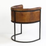 Brown leather armchair with black metal legs, featuring a vintage-modern design perfect for dining or lounge settings.