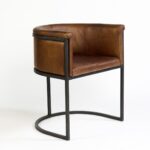 Brown leather armchair with black metal legs, featuring a vintage-modern design perfect for dining or lounge settings.