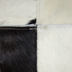 Black and white TAURUS cowhide pouf with natural pattern, ideal for modern and rustic interiors.