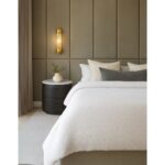 Elegant black oak bedside table with an oval design, stone top, and two drawers, combining natural warmth with contemporary style.