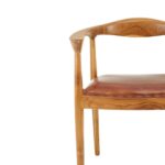 Brown leather chair with natural teak frame, open back, and curved armrests—featuring metallic stud accents for a timeless, handcrafted look.