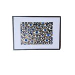 Framed abstract painting with blue and gold eyes on a black background, symbolizing identity and presence.
