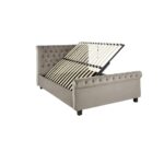 Romir king-size bed with grey velvet upholstery, rolled headboard and footboard, button tufting, and lift-up ottoman storage.
