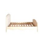 White carved wooden bed with upholstered buttoned panels, featuring a rustic weathered finish and bohemian French-inspired design.