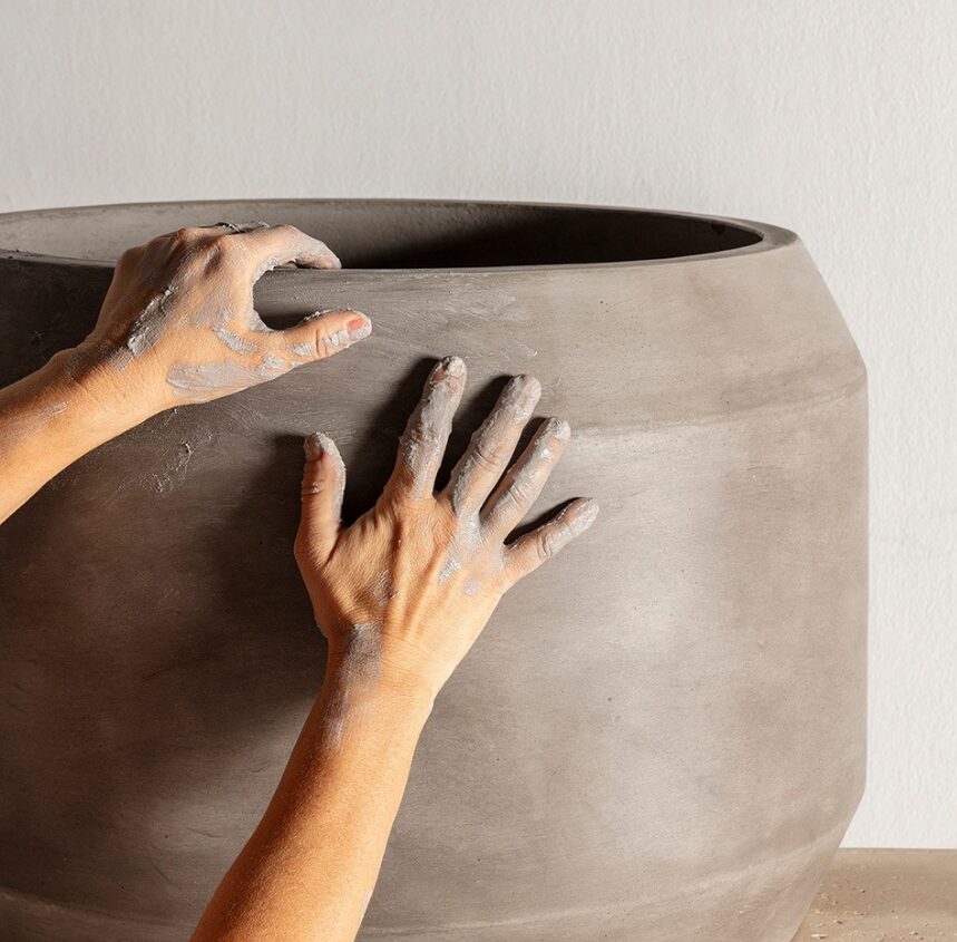 large grey pot in process of being made with hands on image
