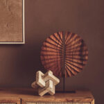 SOREL Brown Wooden Sculpture – handcrafted carved wood disc with radiating segments mounted on black metal base.
