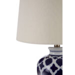 PALOMA Table Lamp with white ceramic base featuring blue quatrefoil motifs, gold metal base and finial, and soft linen shade for elegant ambient lighting.