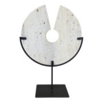 TIBOR Travertine Disc Sculpture featuring a hand-carved circular travertine stone on a sleek black metal base, displayed in a modern living room.