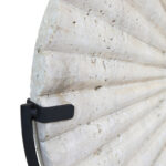 TIBOR Travertine Disc Sculpture featuring a hand-carved circular travertine stone on a sleek black metal base, displayed in a modern living room.