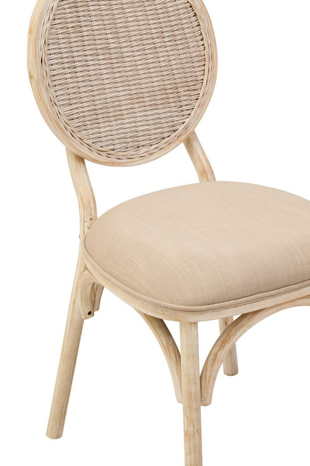 WALTON White Wash Elm Wood Dining Chair featuring cane woven backrest and beige cushioned seat styled in a bright modern dining room.