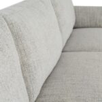 White three-seater sofa with textured fabric upholstery, matching footstool, and slim black metal legs.