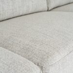 White three-seater sofa with textured fabric upholstery, matching footstool, and slim black metal legs.