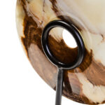 Polished round onyx disc in natural earthy tones displayed on a black metal stand.