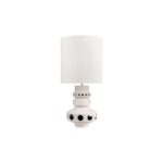 Tall off-white ceramic table lamp with geometric tiered base, circular cut-outs, and a white cylindrical shade.