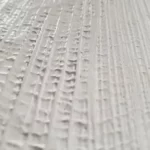 White textured wall art with vertical ribbed detailing and a semi-circular relief in a wooden frame.