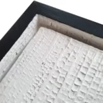 White textured wall art with vertical ribbed detailing and a semi-circular relief in a wooden frame.